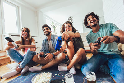 People sat on the floor with gaming consoles in their hands